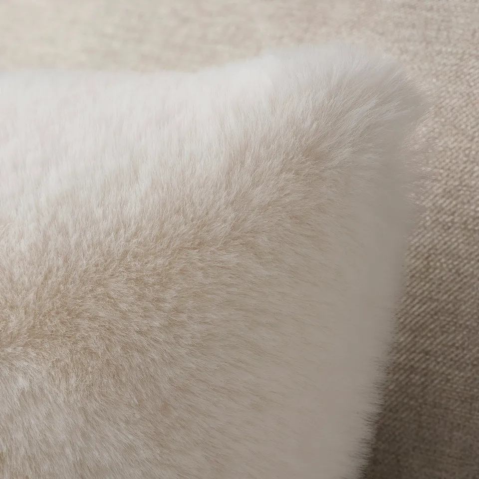 Soft, fluffy, white fur-like texture, likely of a cushion cover, feels smooth and luxurious.