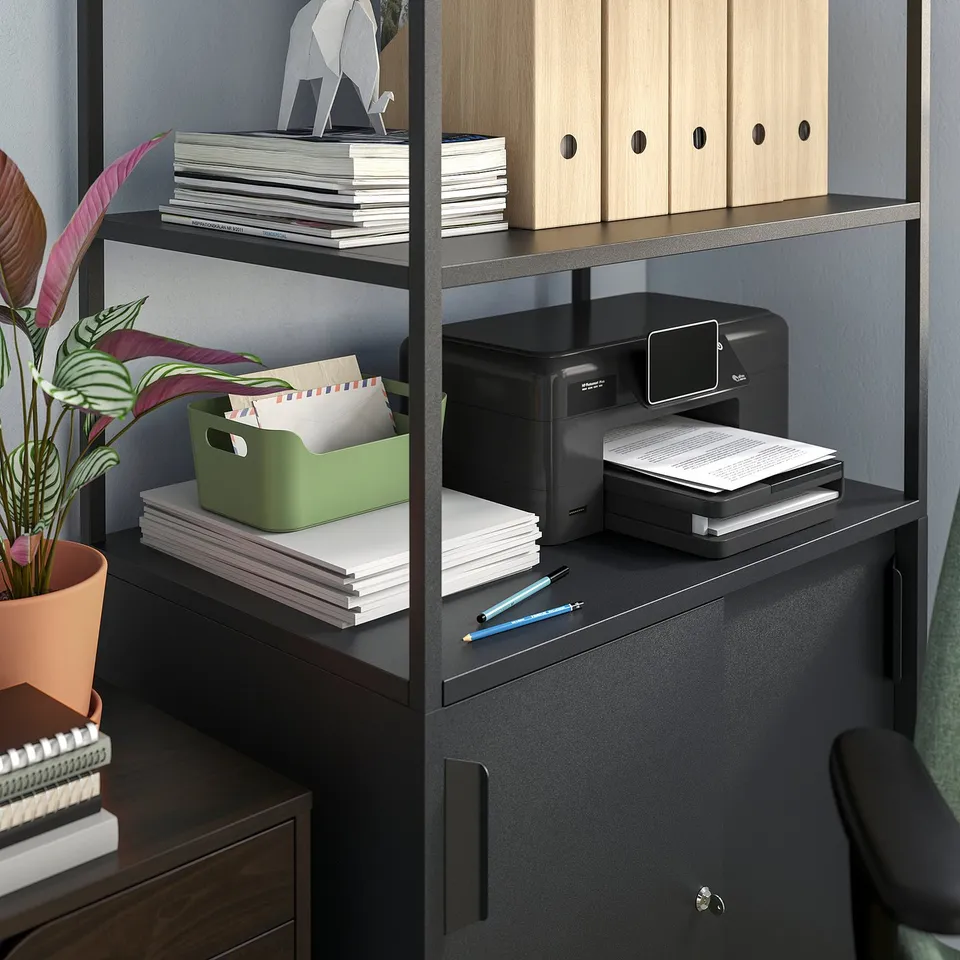 A TROTTEN black double-sided office cabinet with open and closed storage, a printer, and a plant.