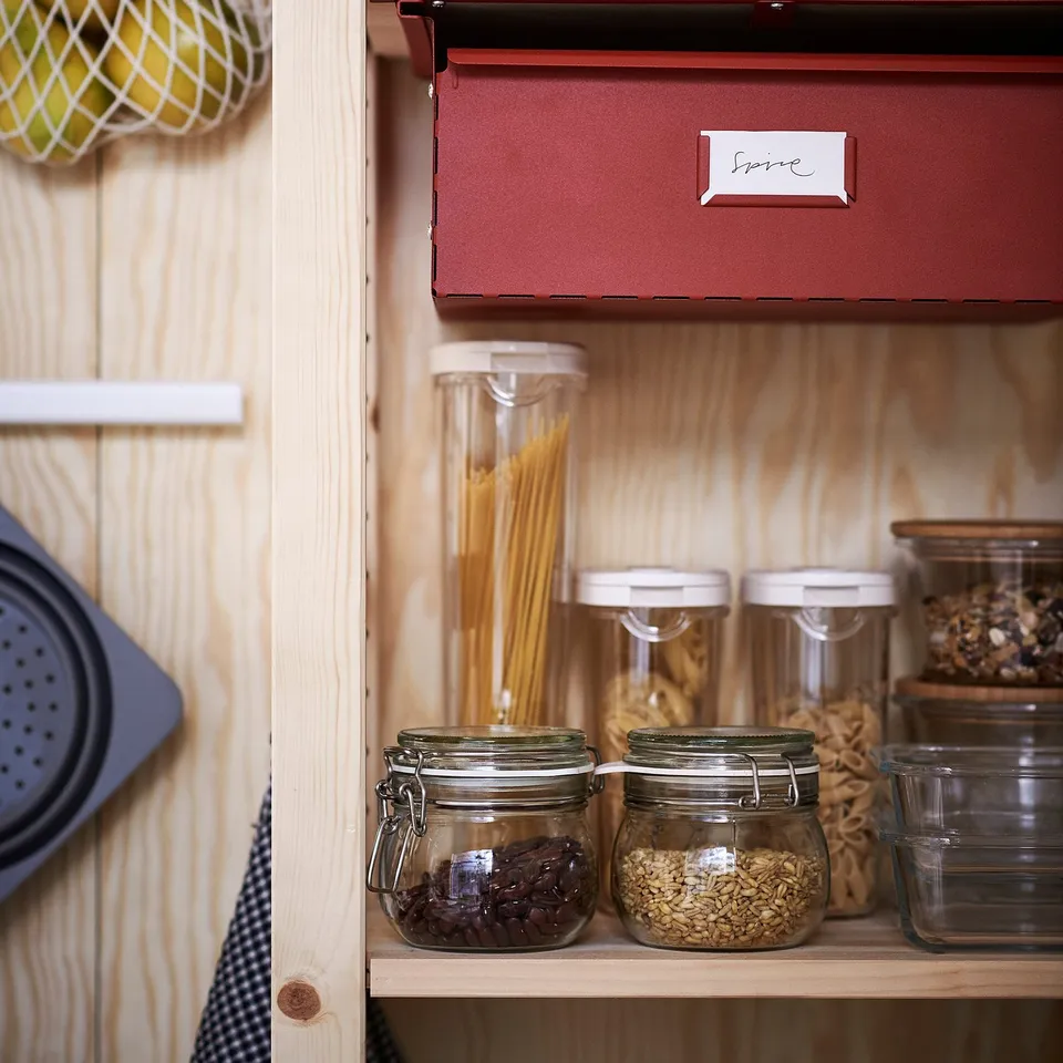 Wooden shelf with glass jars storing dry foods, labelled red box above.