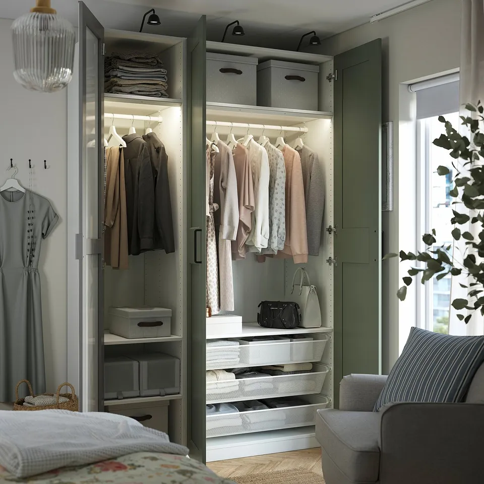Open wardrobe with clothes, accessories, and storage. Mirrored doors expand space. Integrated lighting illuminates contents.