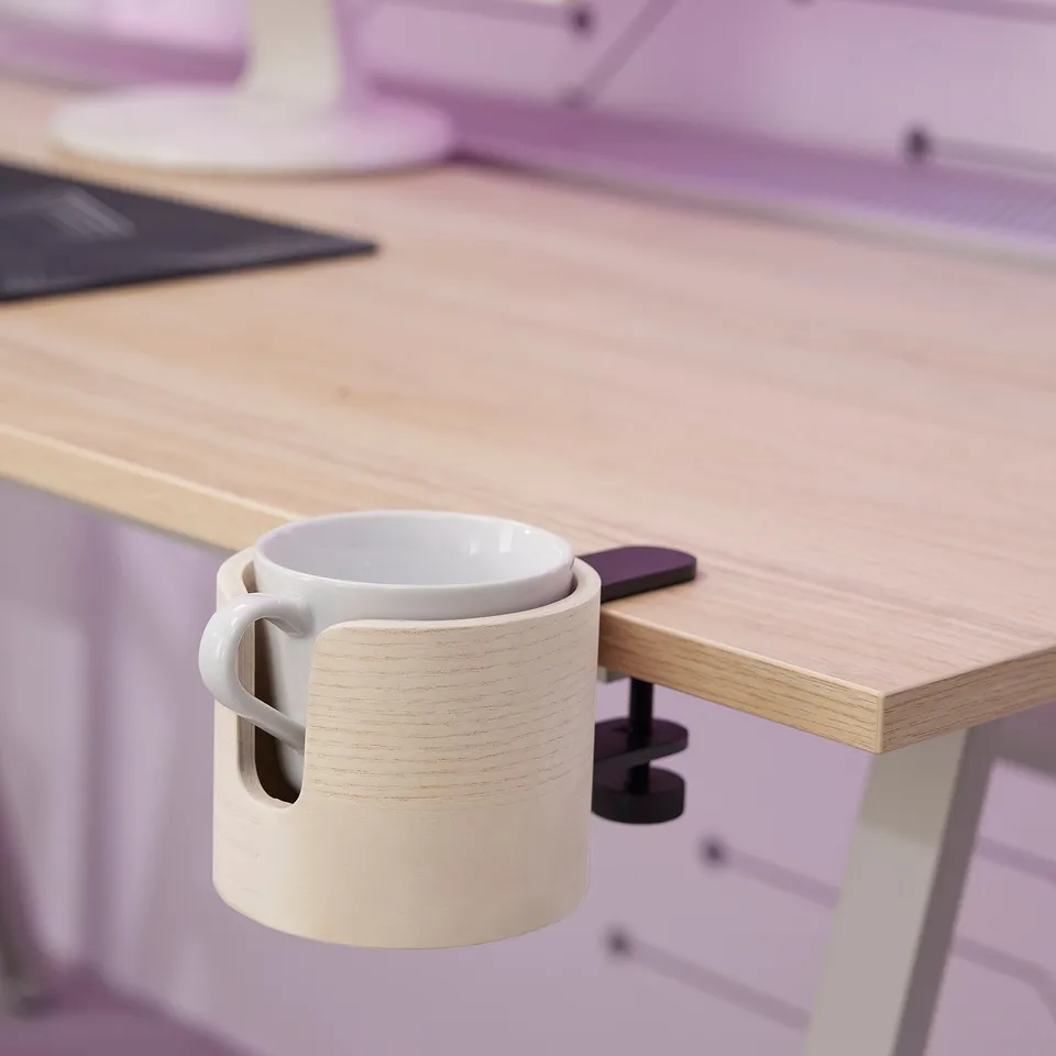 A wooden mug holder clamped to a desk, holding a white ceramic mug safely away from a keyboard and mouse.