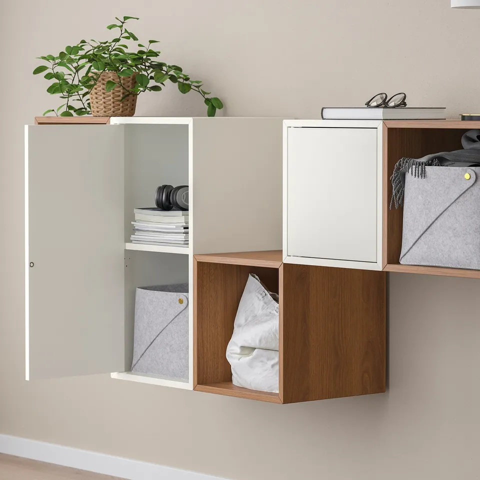 Wall storage with open/closed compartments. Holds cloth, books, headphones, plant. Doors have integrated openers.