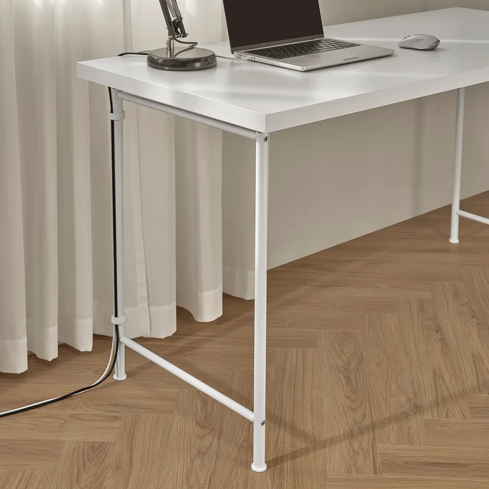 Desk with laptop, mouse, and lamp. Cable management visible, adjustable feet for stability.