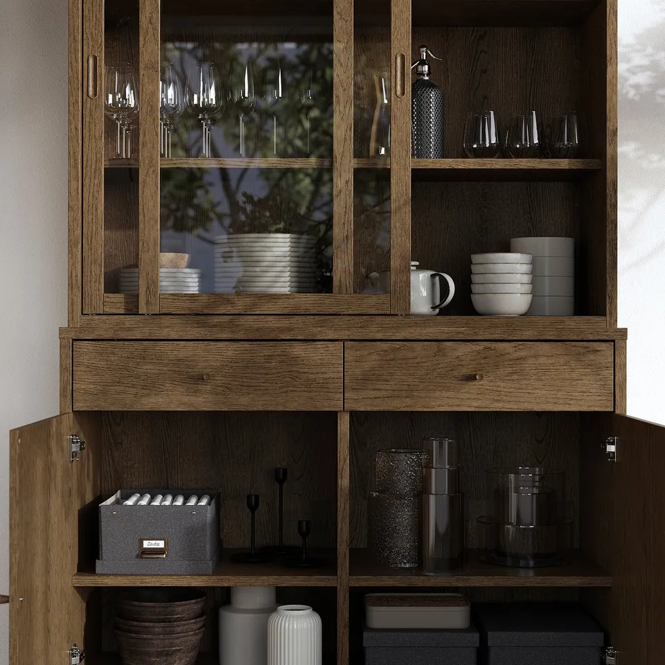 Wooden cabinet with glass doors displaying dishes and glasses. Has drawers and shelves for storage, and interior lighting prepared.