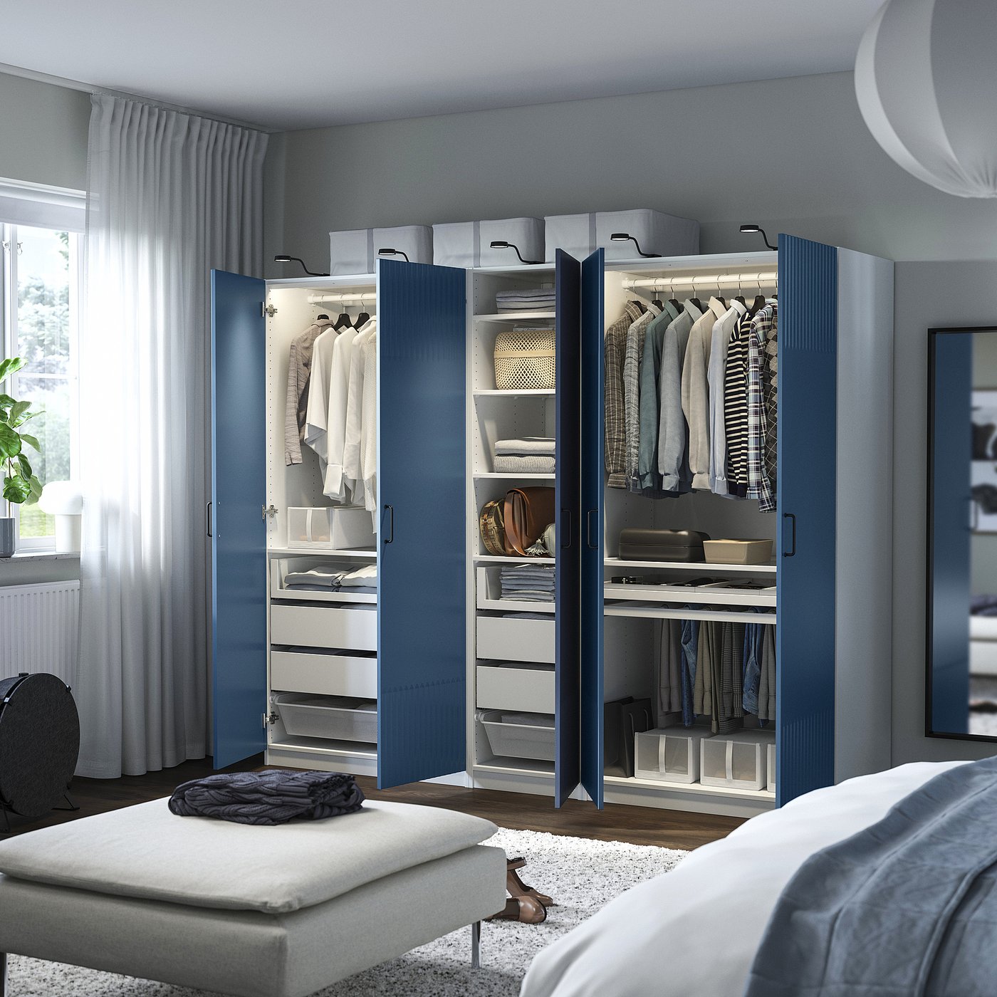 Open blue PAX wardrobe showing clothes, shelves, drawers, and internal lighting.