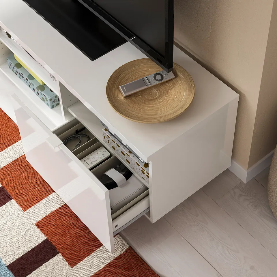 White tv stand with open and closed storage, adjustable shelves inside, remote control on top, tv is supported up to 50 kg.