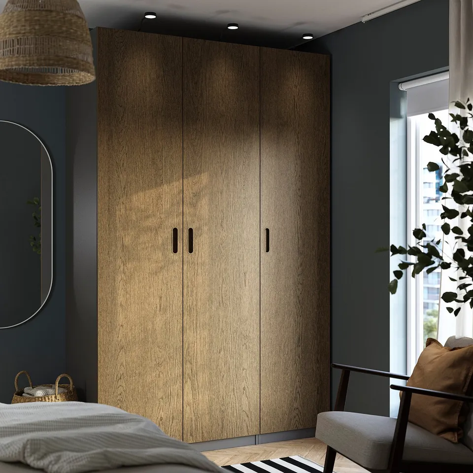 Modern bedroom with large wooden closet, grey walls, bed, chair, and window.
