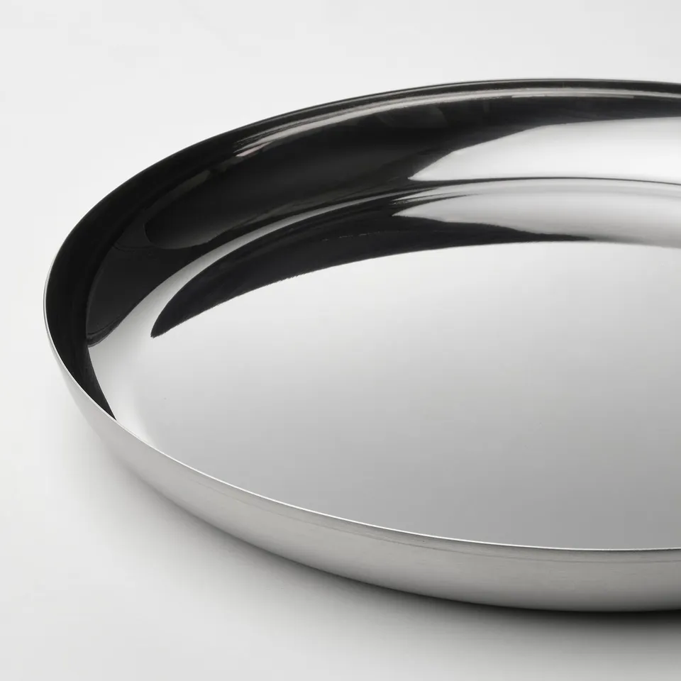 Shiny stainless steel serving plate. Curved, reflective edge. Sleek, polished surface.