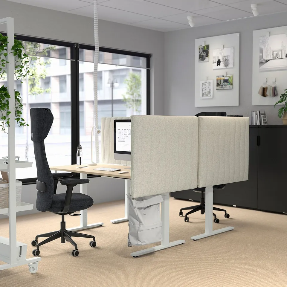 Modern office setup with MITTZON standing desks in beige and grey. Includes grönfjäll chair, acoustic screens, and large windows.