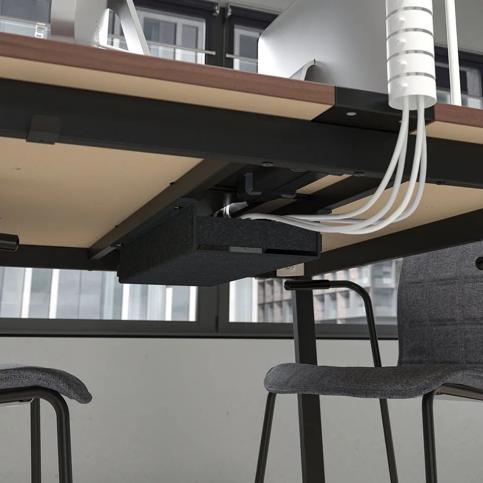 Under-desk cable management system with footrest for support.