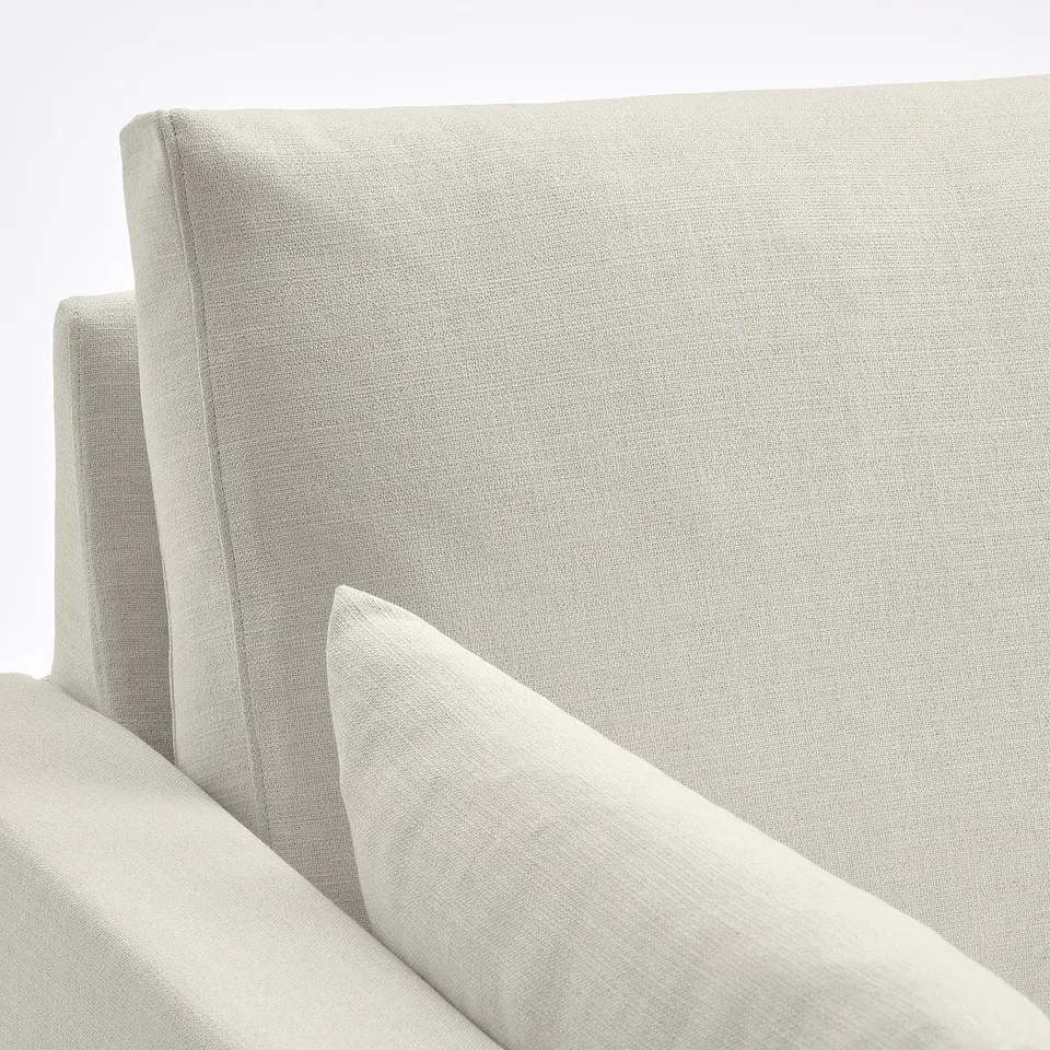 Close-up of HYLTARP sofas soft, light-colored fabric. Clean lines, inviting texture.