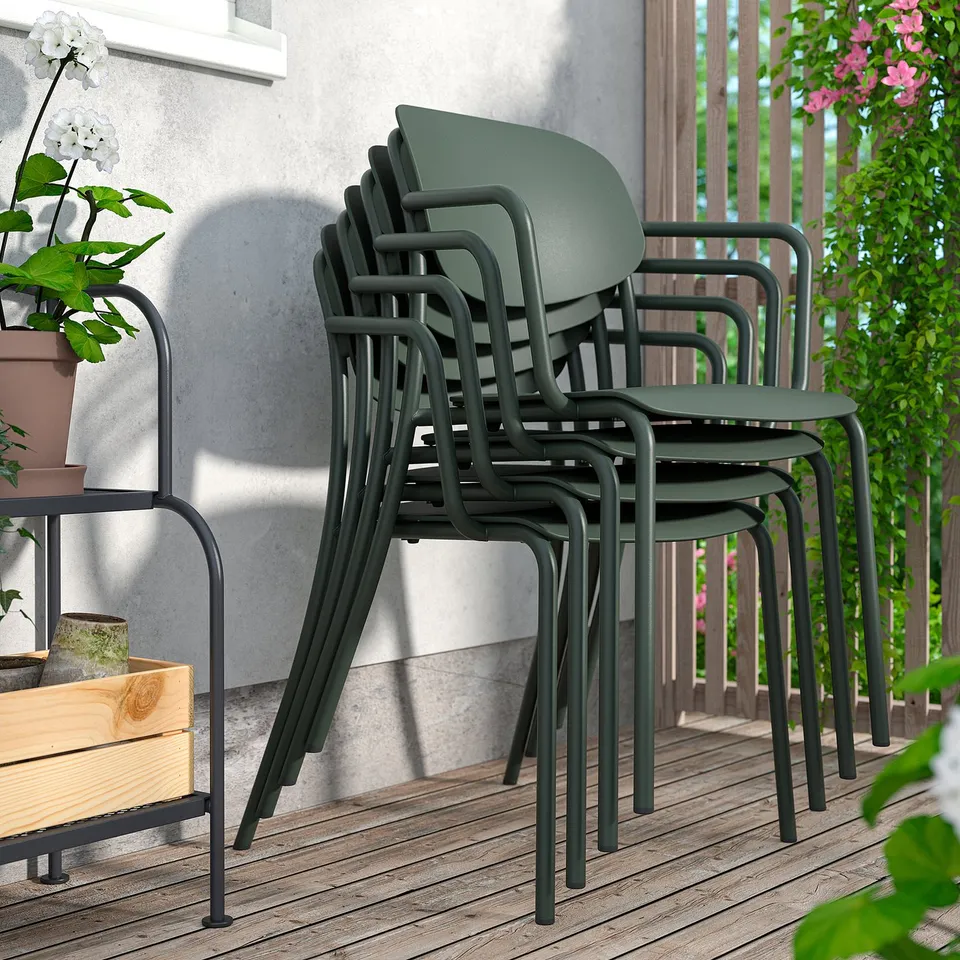 Stacked VISINGSÖ outdoor chairs, dark green, on wood deck by wall.