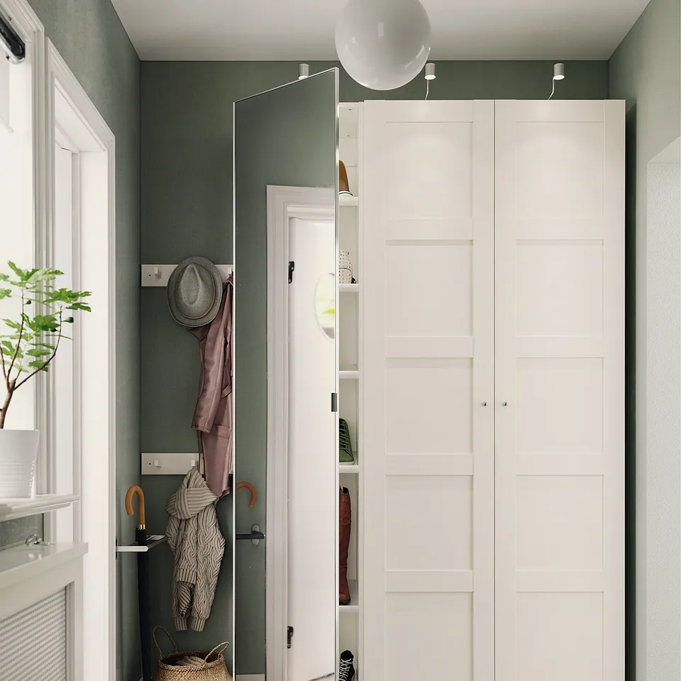 Neat hallway with white ÅHEIM mirror door, green walls, dark floor, and hanging coats and hats.