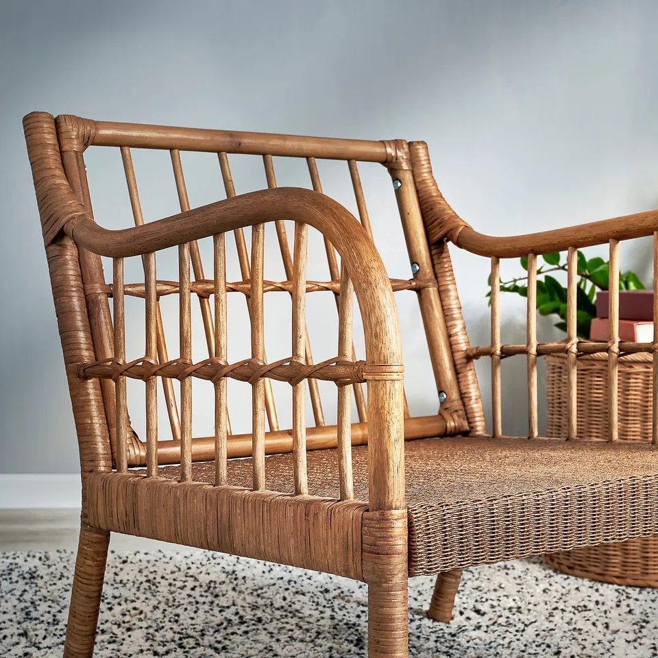 Handwoven rattan armchair with bamboo details, featuring a curved backrest and armrests, placed on a textured rug.