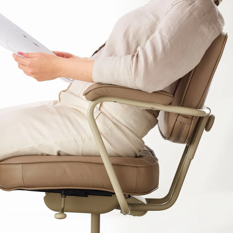 Person adjusting lumbar support on an ergonomic office chair. Beige leather and metallic frames visible.