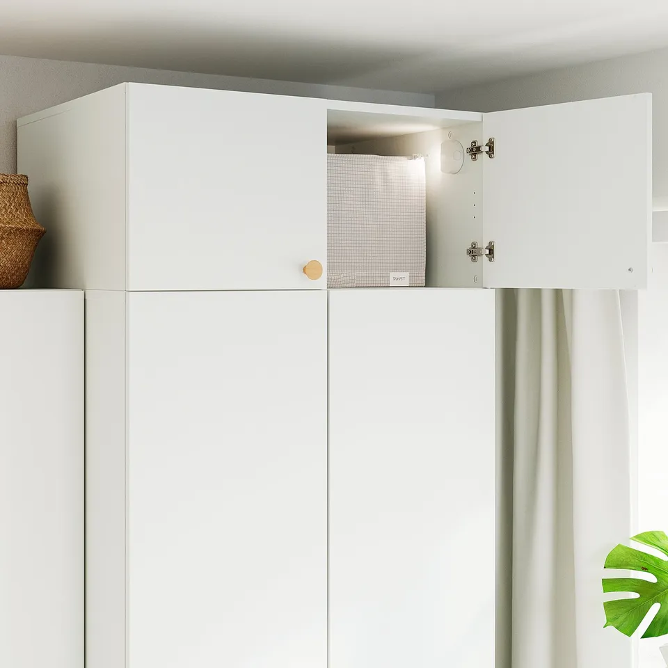White cabinet with one door open revealing storage box inside. Hinges visible.