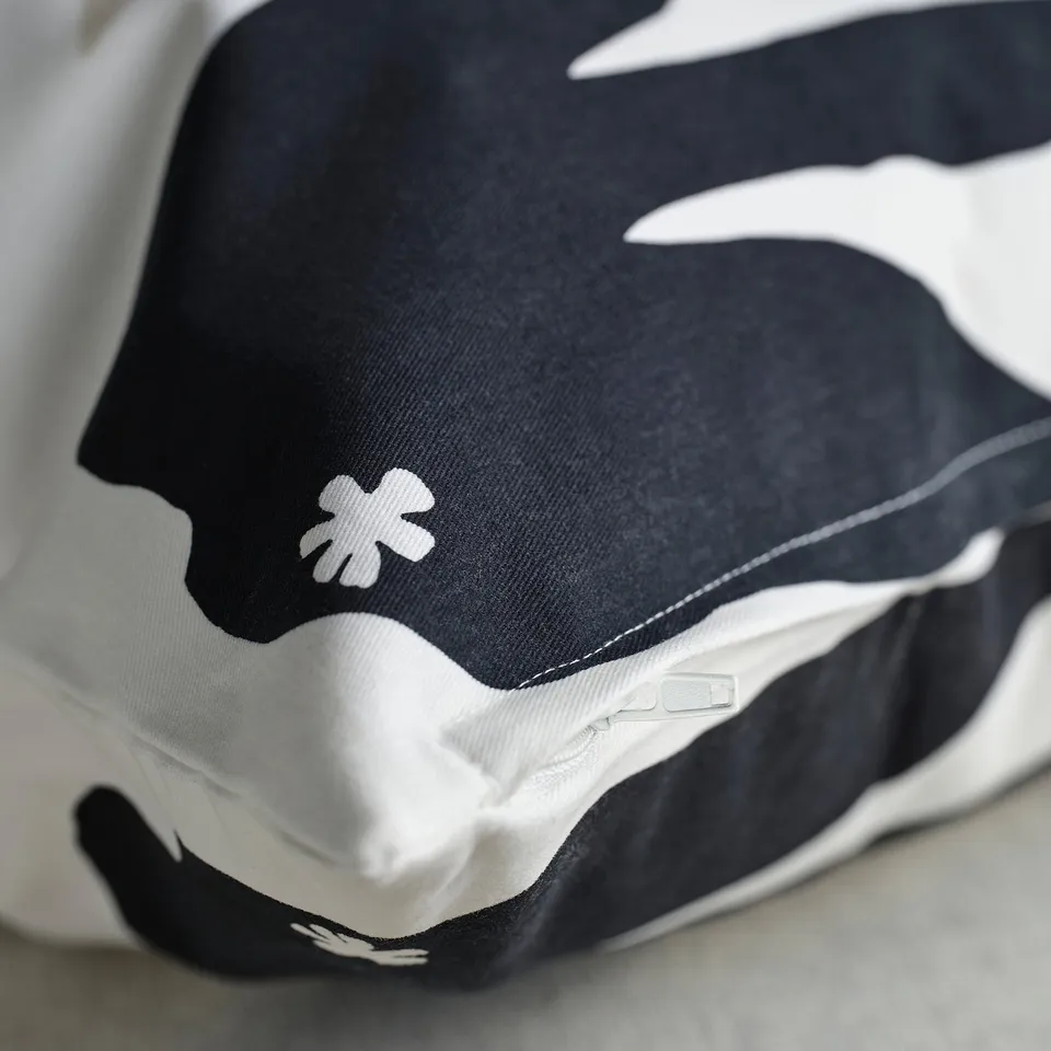 Black and white cushion with floral design, zip detail, soft texture.