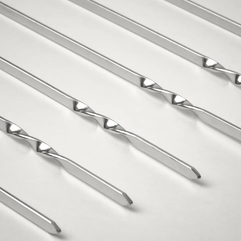 Multiple metallic grill skewers arranged neatly, showcasing their polished, flat design and sharp tips.