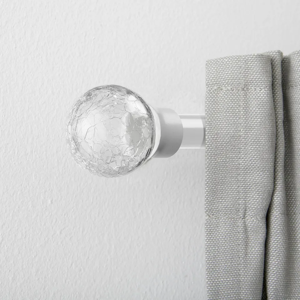 A spherical glass finial on a curtain rod, serving as a stylish end piece to enhance window treatments.