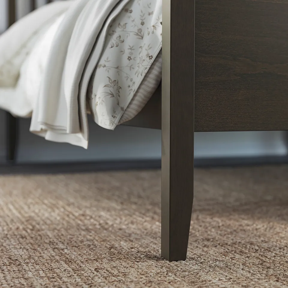 Modern bed frame with dark wood legs and beige patterned headboard.