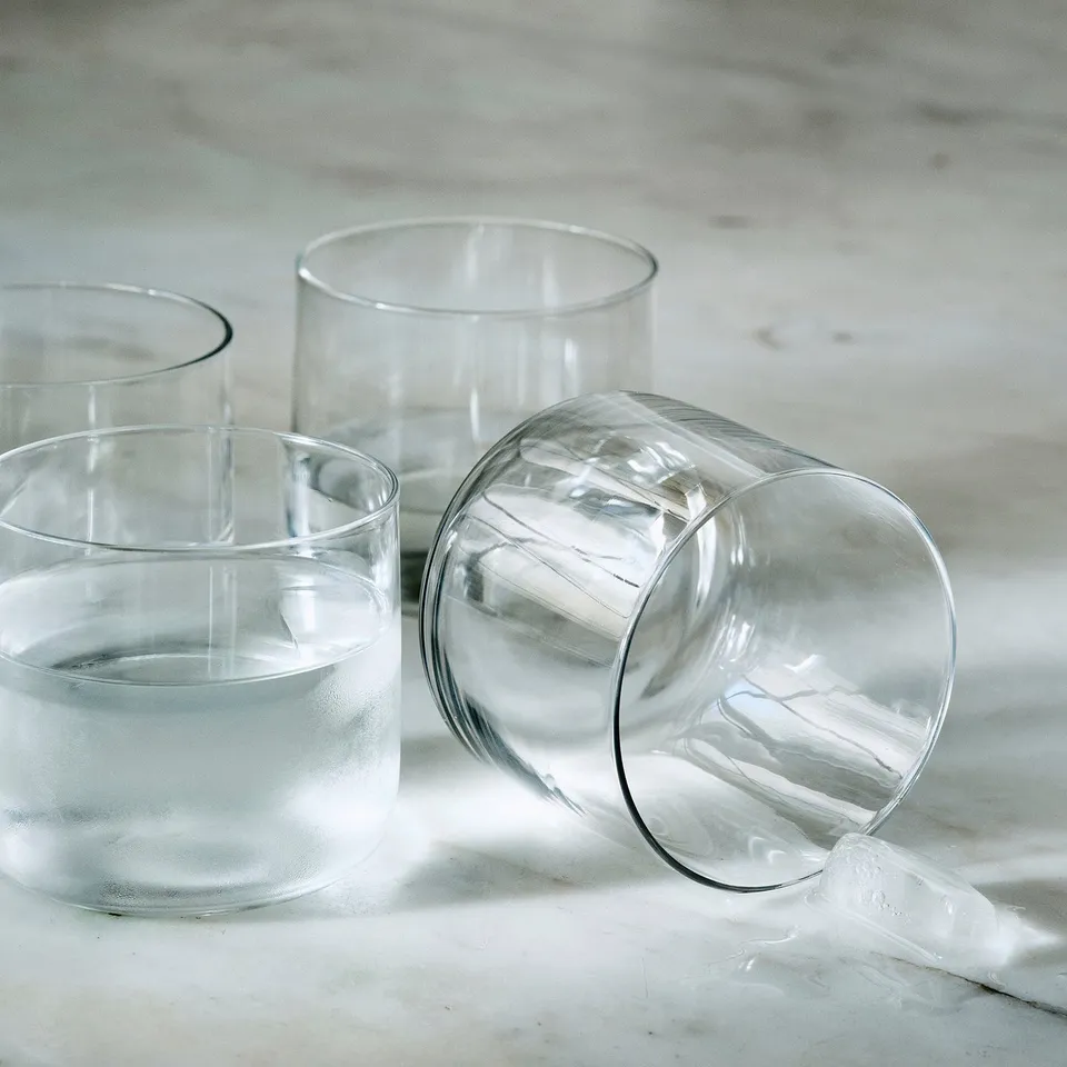Four sleek glass cups on light surface.