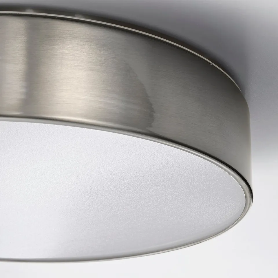 Close-up of a modern, brushed nickel ceiling lamp with smooth metal finish and frosted acrylic light diffuser.