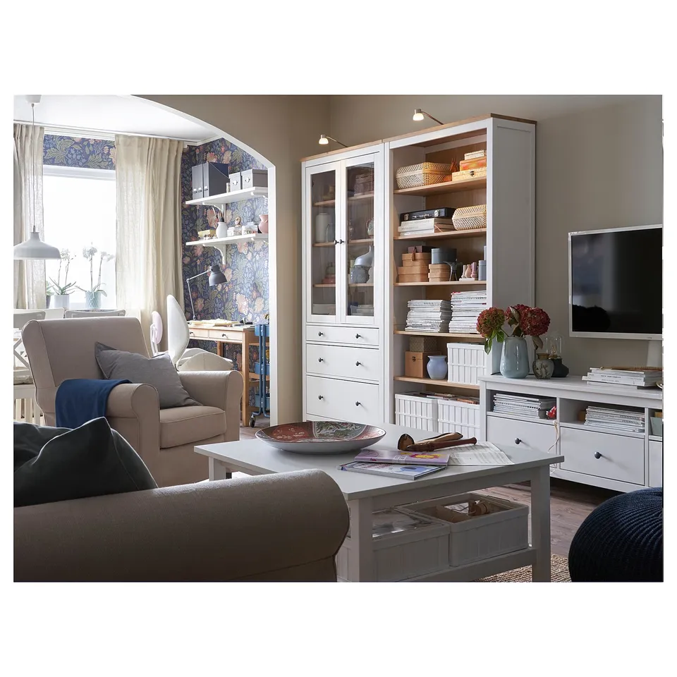 Modern living room with brown sofa, white HEMNES storage units, beige walls, and floral curtains.