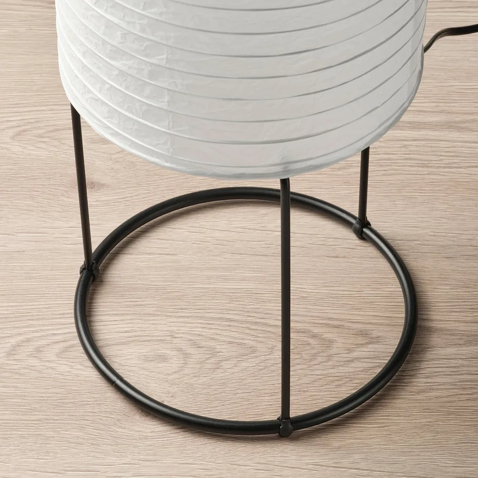 Modern floor lamp with a round rice paper shade and black metal base. Soft, diffused lighting.