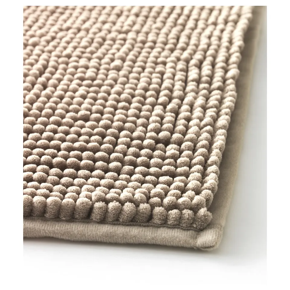 Close-up of a soft, textured bath mat with small, rounded loops, set against white.