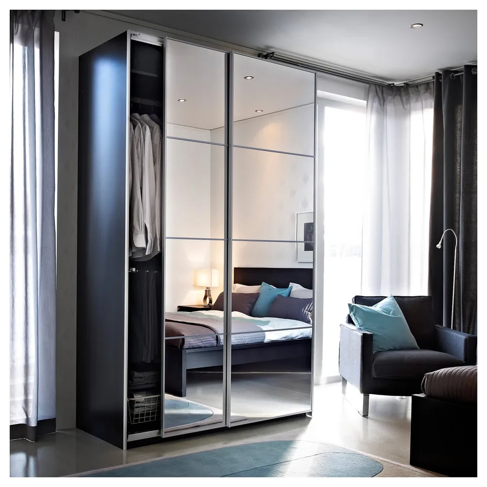 Modern bedroom with mirrored closet and dark grey chair.