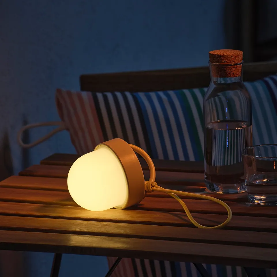 Solar lamp on table, lit, with chair and water bottle.
