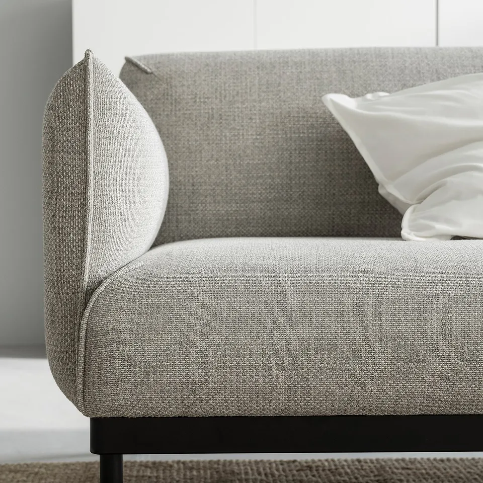 Modern grey sofa with sleek black legs and white pillows.