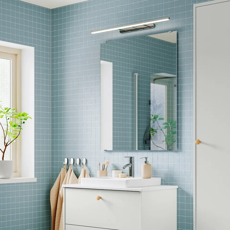 Modern bathroom with blue tiles, white cabinet, and FLASKPOST led light.