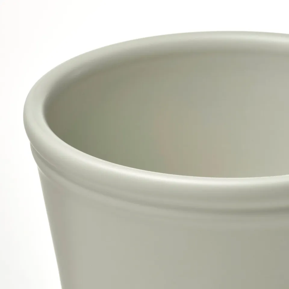Close-up of a smooth, light green planter made of earthenware, showcasing its simple and durable design.