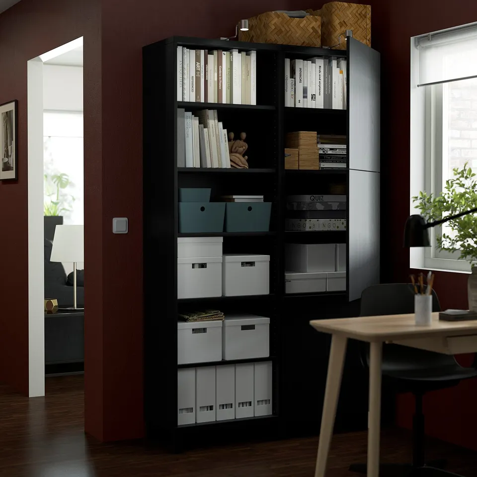Black BESTÅ storage unit with adjustable shelves, organising books, boxes, and decorative items. Open and closed storage compartments.