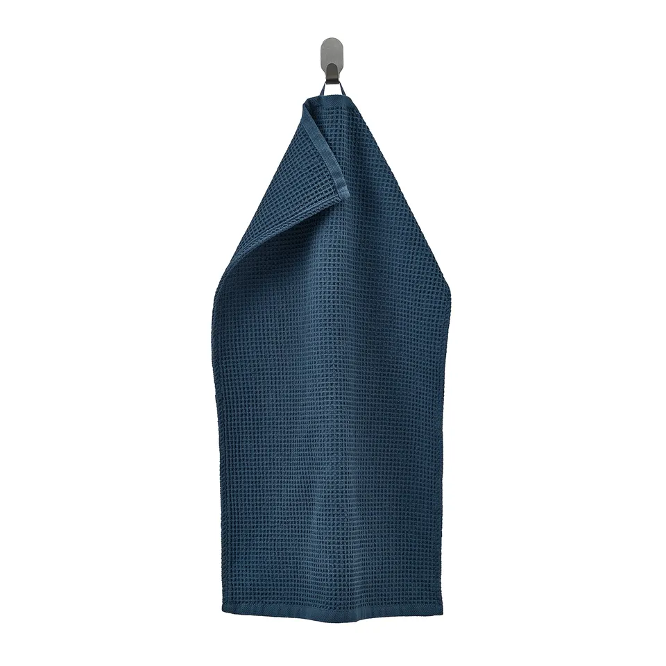 A navy blue GULLDYNA towel hanging on a hook, made of 100% cotton, rectangular with a textured weave design.