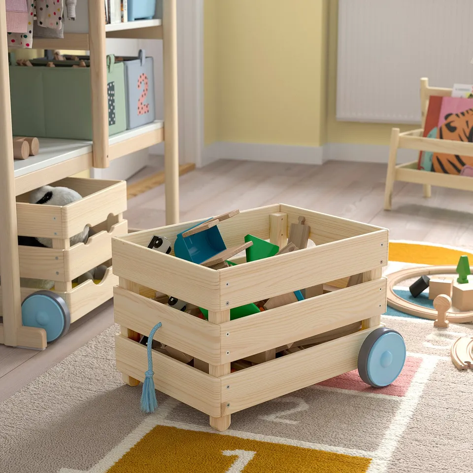 Childrens wooden toy cart with wheels, filled with colourful blocks, on a rug in a playful room.