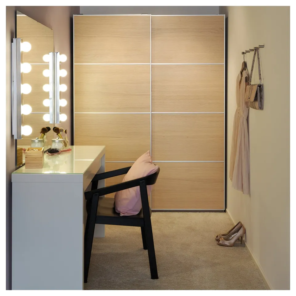 Modern dressing table with vanity mirror, black chair, and light-colored wardrobe.