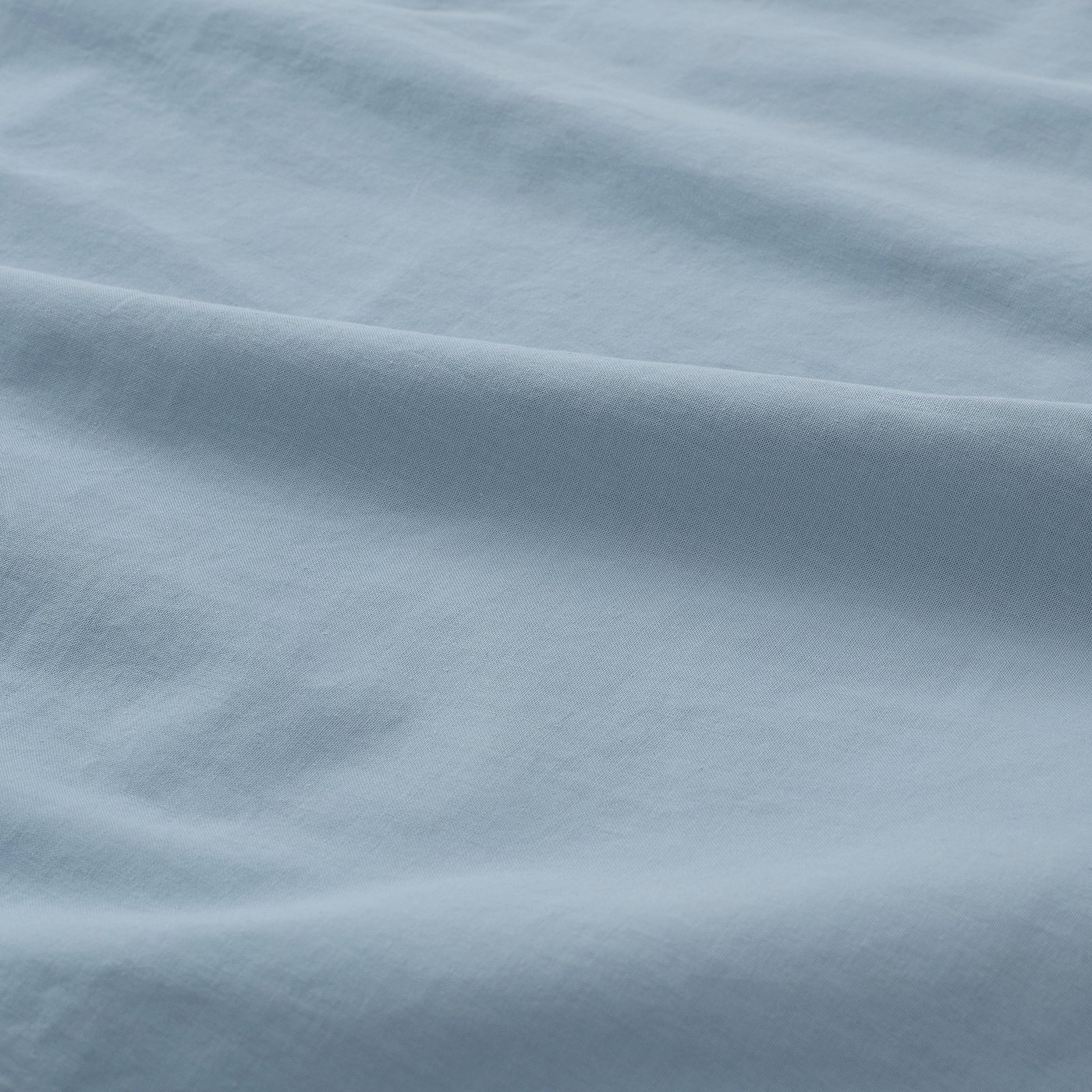 Close-up of soft, textured light blue pillowcase showcasing fine weave and smooth fabric.