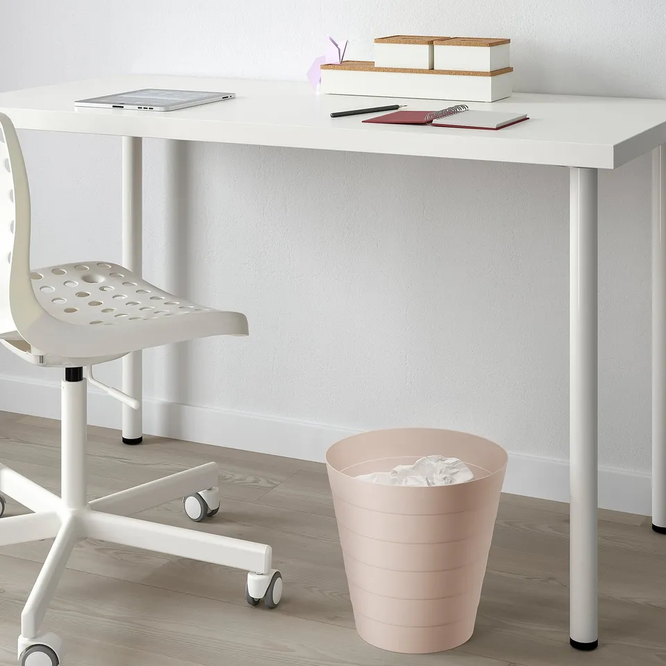 White desk with laptop and pink rubbish bin.