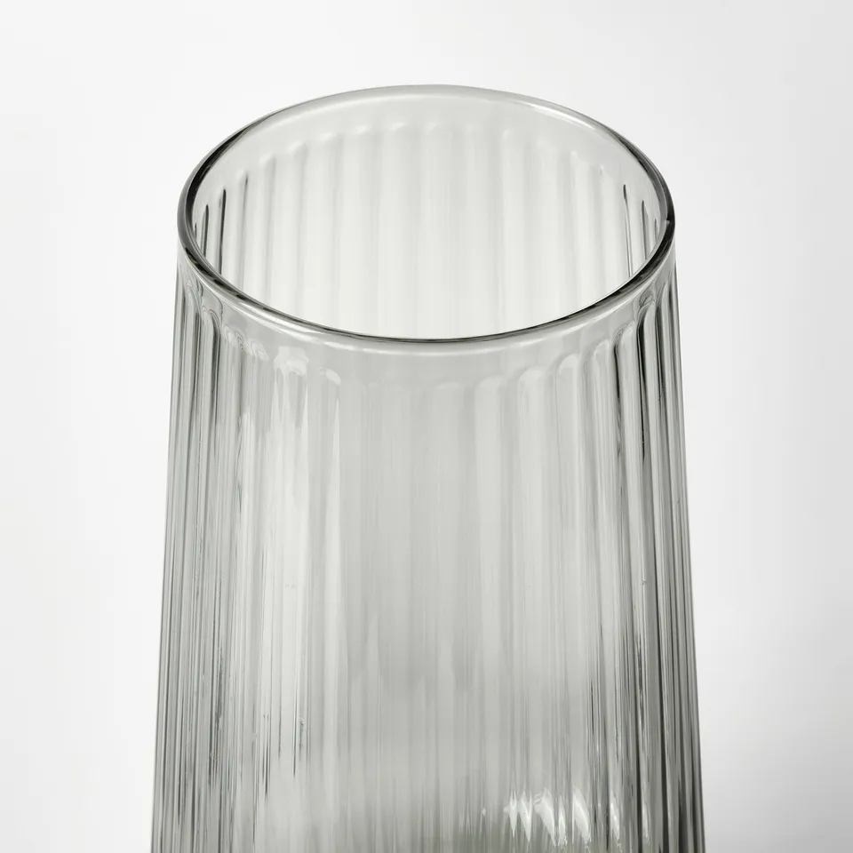 Clear glass vase with ribbed texture, standing upright against white background.