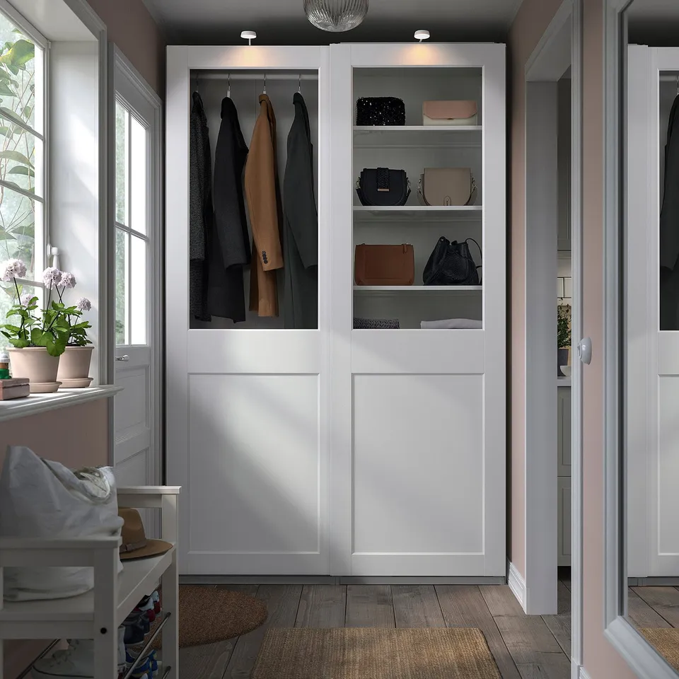 Modern PAX wardrobe with glass doors, clothes, accessories, and towels.