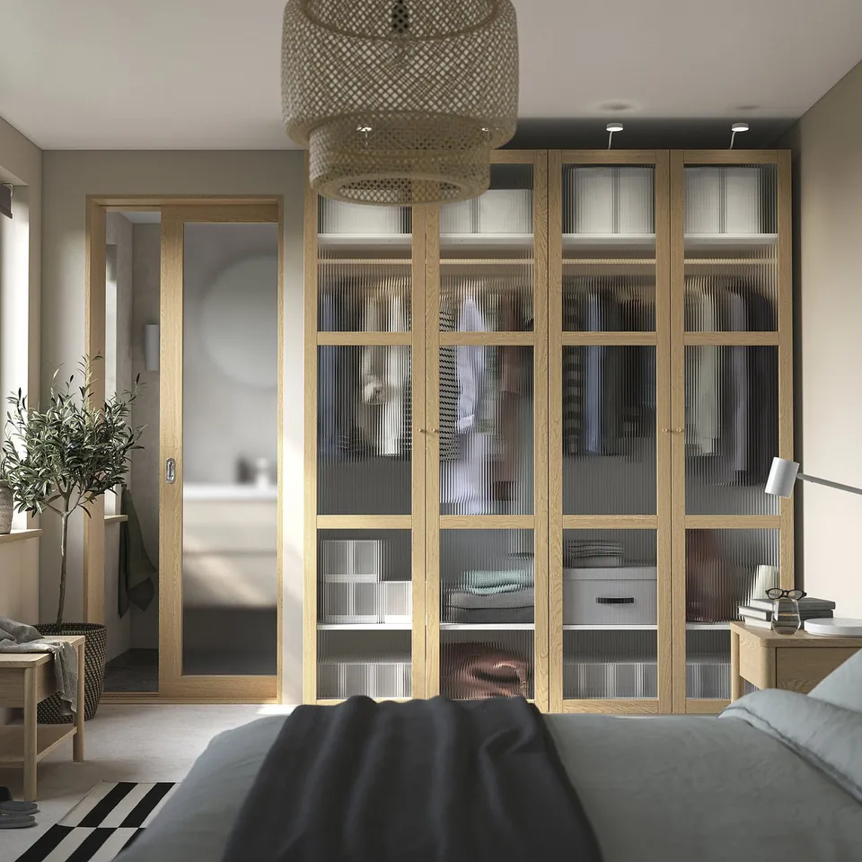 Modern bedroom with PAX wardrobe, pendant light, cosy bed, bathroom access, and plant.