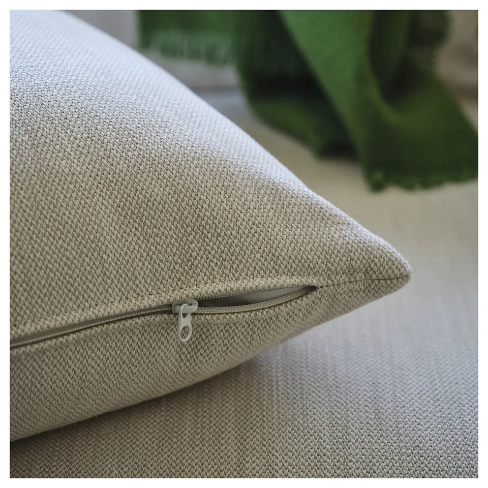 A close-up of a beige sofa with a visible wooden frame and zip.