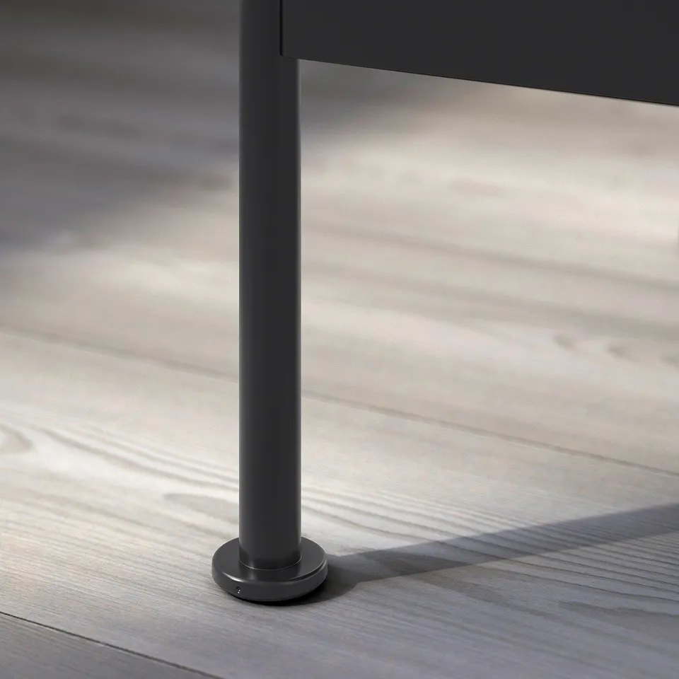 Modern, black metal table leg with adjustable foot; sleek, industrial design.