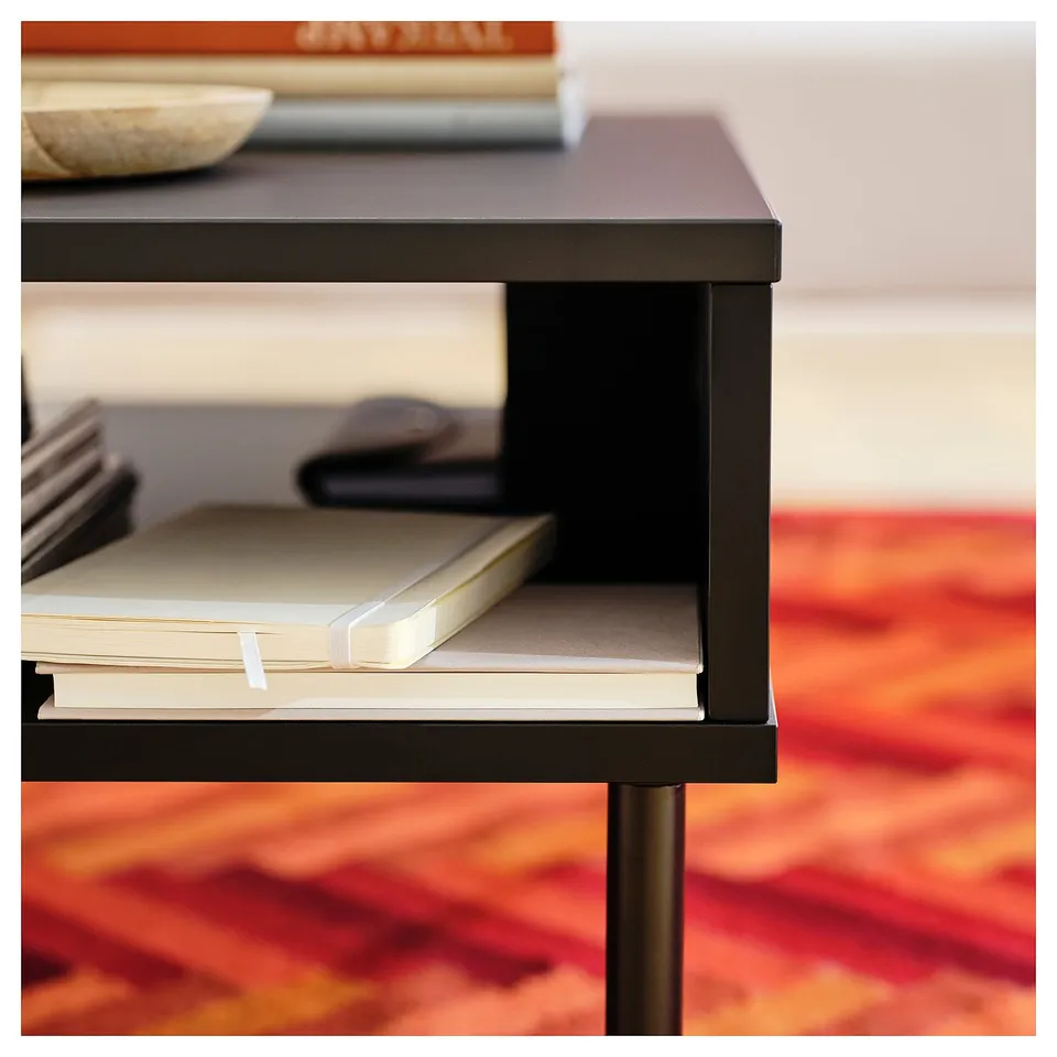 Black TUNSTA side table with books on shelves, modern design.