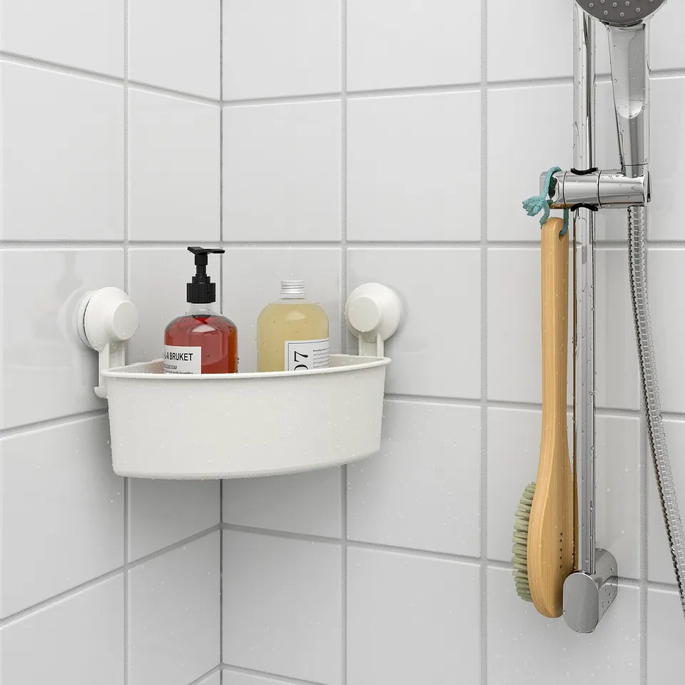 Plastic corner caddy in shower holds soap dispenser and bottles. Mounts on tiled wall with suction cups.