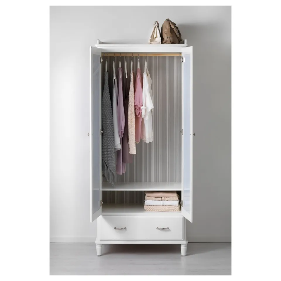 White TYSSEDAL wardrobe with open doors, displaying clothes on hangers, folded clothes on shelves, and bags on top.