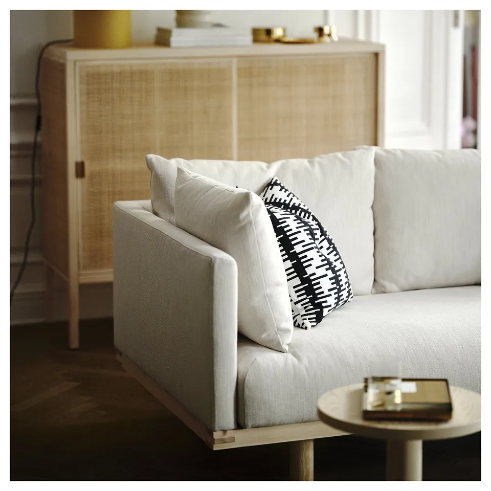 Minimalist white sofa, black & white pillow, wooden side table, wicker cabinet.