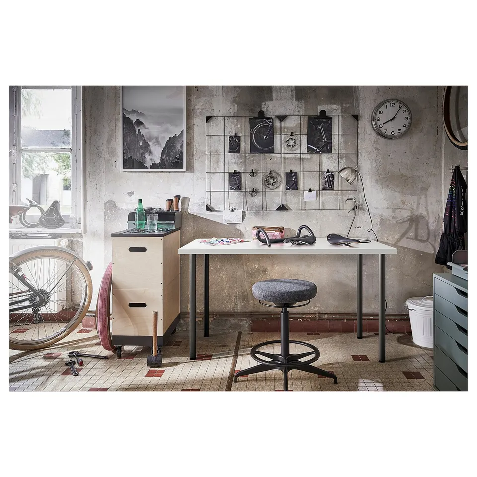 Industrial-style workspace: LAGKAPTEN white table, grey stool, vintage decor, bike, tools.